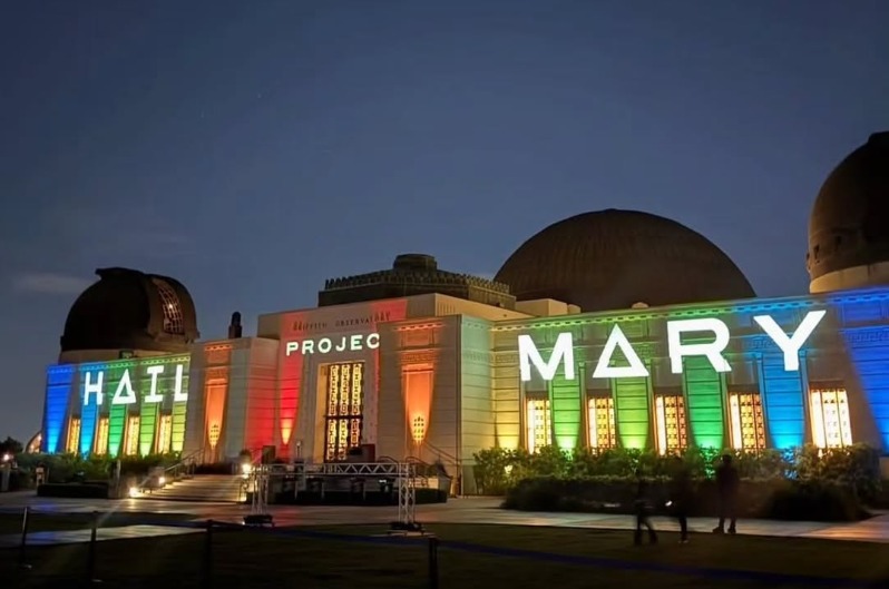 Illuminated HAIL MARY title lettering across the Griffith Observatory facade at night