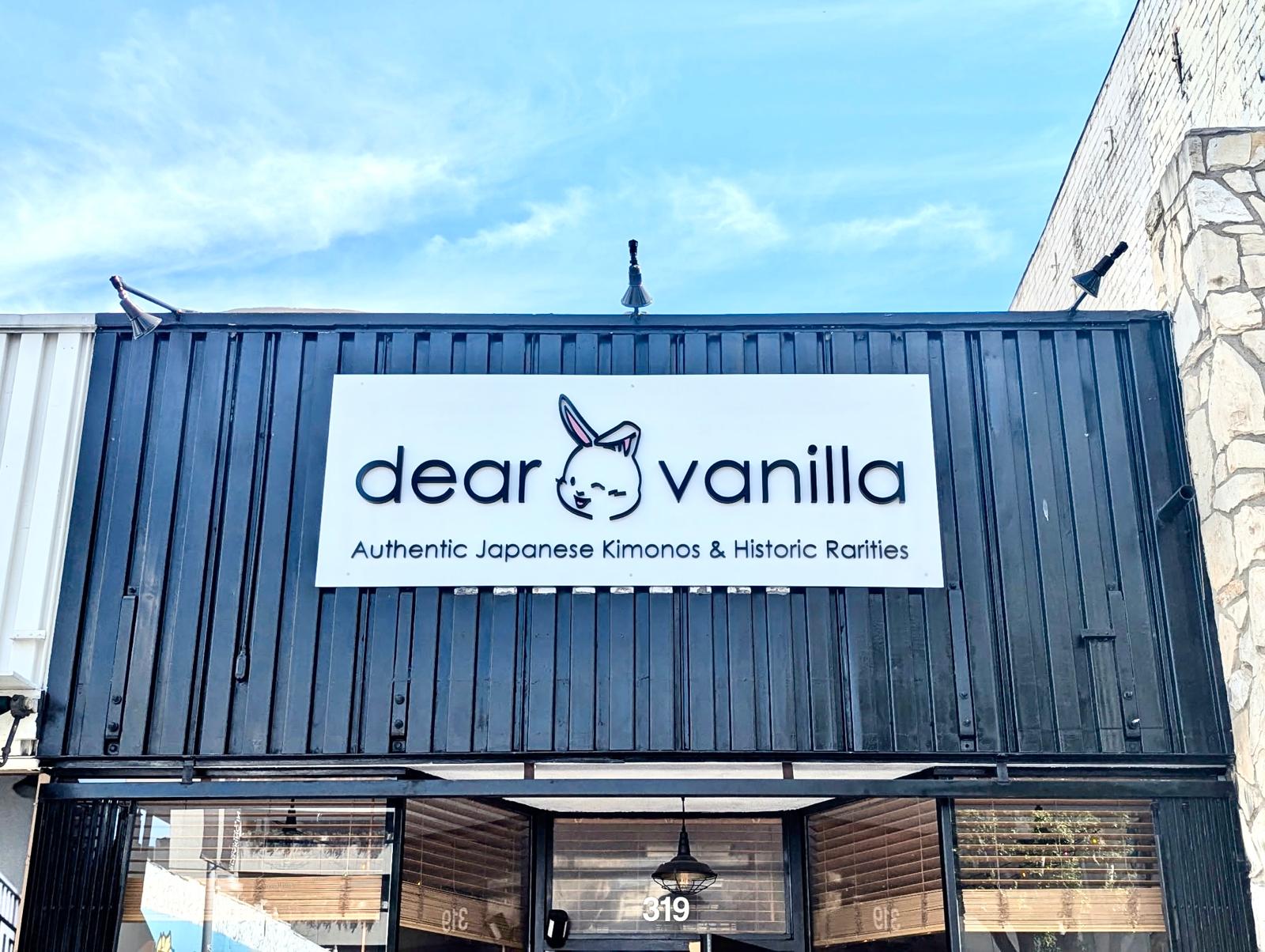 Dear Vanilla storefront sign with black dimensional letters and a rabbit logo on a white panel mounted to a black container facade