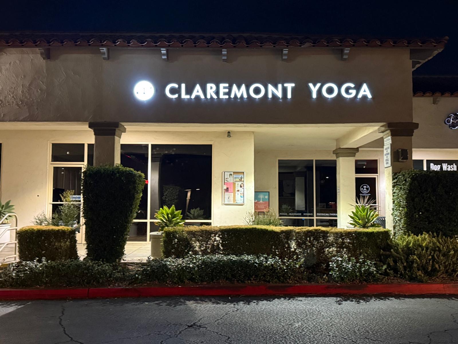 Claremont Yoga storefront at night with bright white illuminated channel letters and circular logo